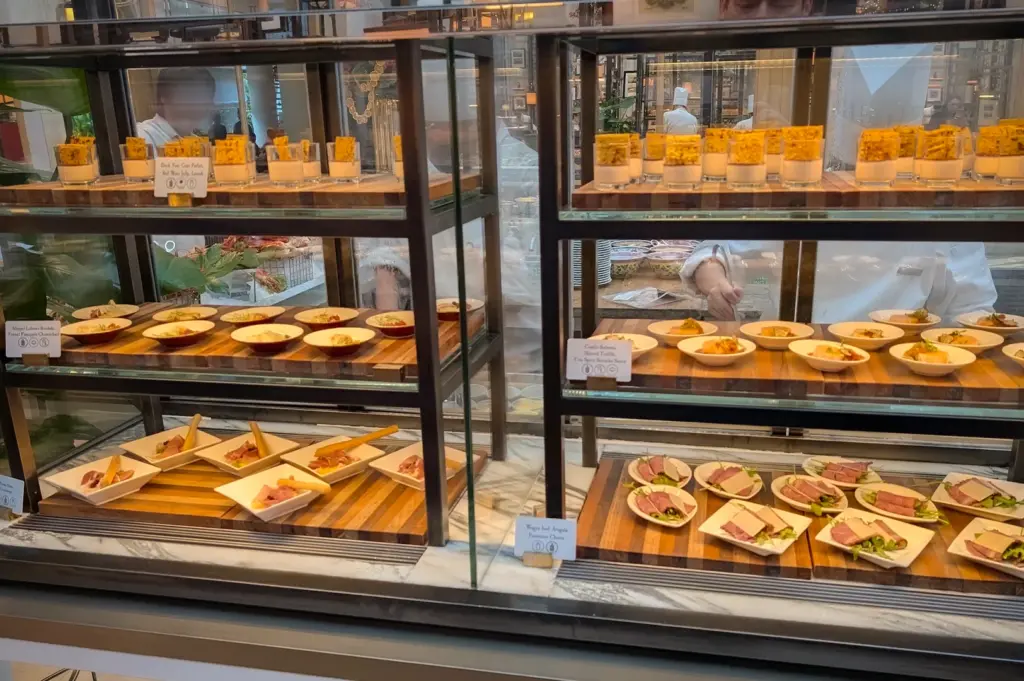Gourmet brunch appertizers and small plates, including Wagyu beef and seafood parfaits, displayed on tiered wooden shelves at the Colony restaurant buffet in Singapore.